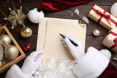 Photo of Top view of Santa writing letter at wooden table, closeup