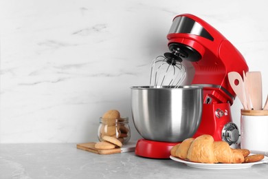 Photo of Modern red stand mixer, croissant and cookies on light gray marble table. Space for text