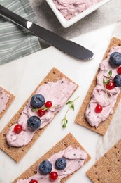 Tasty cracker sandwiches with cream cheese, blueberries, red currants and thyme on table, flat lay