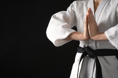 Man wearing keikogi and black belt on dark background, closeup view with space for text. Martial arts uniform