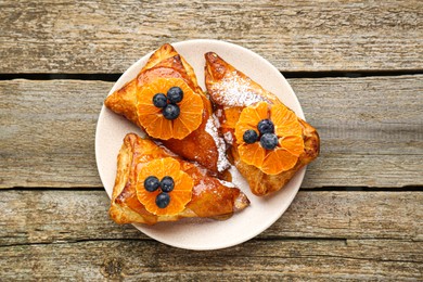 Photo of Fresh tasty puff pastry with sugar powder, jam, tangerines and blueberries on wooden table, top view
