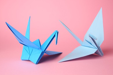 Photo of Origami art. Handmade paper cranes on pink background, closeup