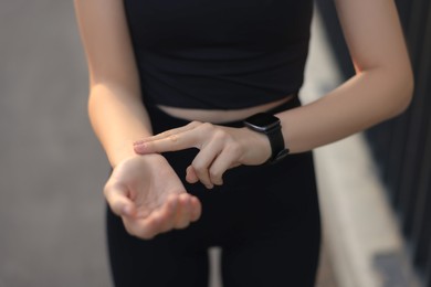 Woman checking pulse after training outdoors, closeup