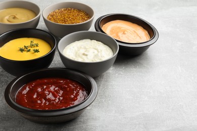 Many different sauces on grey table, space for text