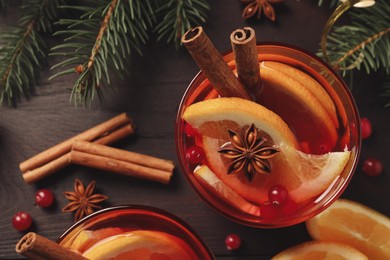 Delicious punch drink with cranberries, orange and spices on wooden table, flat lay
