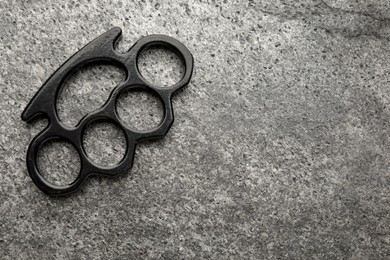 Black brass knuckles on grey background, top view. Space for text