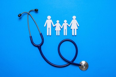 Photo of Paper family cutout and stethoscope on light blue background, flat lay. Insurance concept