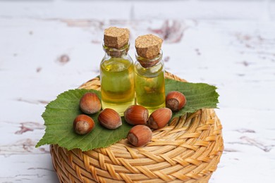 Bottles of hazelnut essential oil and nuts on table
