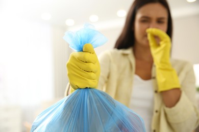 Woman holding full garbage bag at home, focus on hand