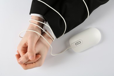 Man showing hands tied with mouse cable on white background, top view. Internet addiction
