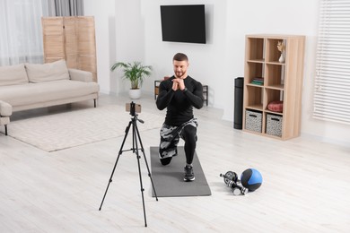 Photo of Trainer streaming online workout with phone at home