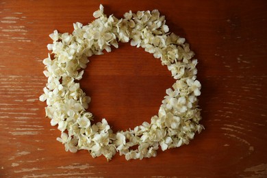 Frame made of beautiful white jasmine flowers on wooden table, flat lay. Space for text