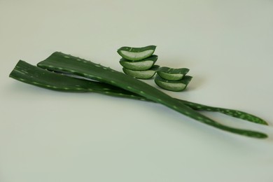 Green aloe vera leaves and slices on light background