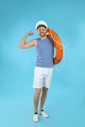Sailor with ring buoy showing biceps on light blue background