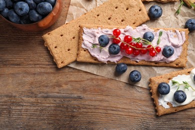 Tasty crispy crackers with cream cheese, thyme and berries, flat lay. Space for text