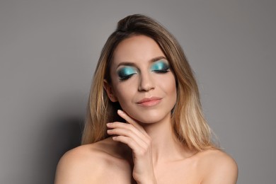 Young woman with evening makeup on grey background. Eye shadow product