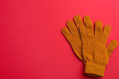 Pair of stylish woolen gloves on red background, flat lay. Space for text