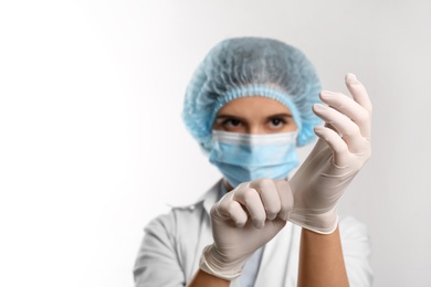Doctor putting on medical protective glove against white background