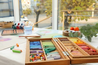 Artist's workplace with drawings, soft pastels and color pencils on table indoors