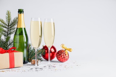 Happy New Year! Bottle of sparkling wine, glasses and festive decor on white background, space for text