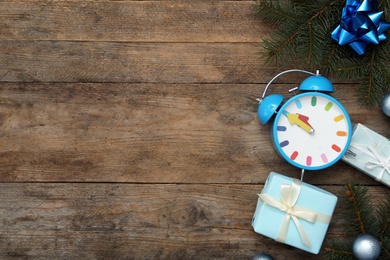 Photo of Flat lay composition with alarm clock and Christmas decor on wooden background, space for text. New Year countdown