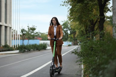 Young businesswoman riding electric kick scooter outdoors
