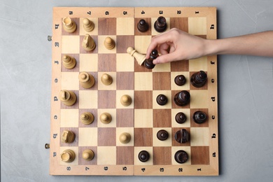 Woman playing chess on grey background, top view. Victory concept