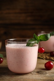 Tasty fresh milk shake with cherries on wooden table