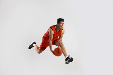Professional sportsman playing basketball on grey background