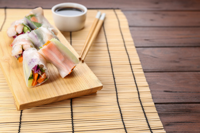 Delicious rolls wrapped in rice paper served on wooden table