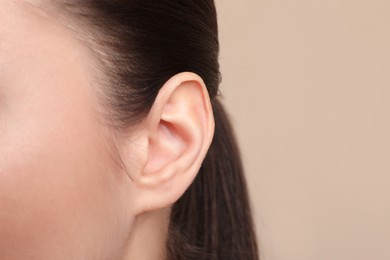 Photo of Woman on beige background, closeup of ear. Space for text