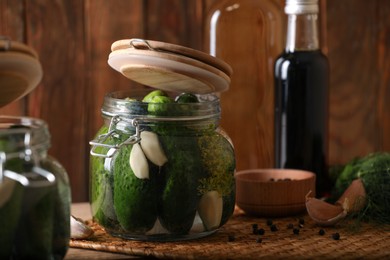 Photo of Glass jars with fresh cucumbers ready for canning on wooden table
