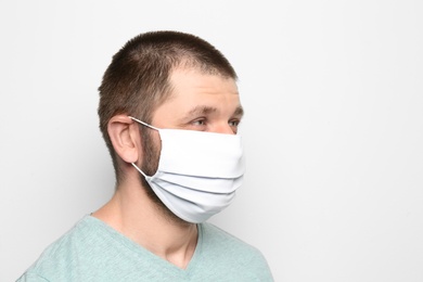 Man wearing handmade cloth mask on white background, space for text. Personal protective equipment during COVID-19 pandemic