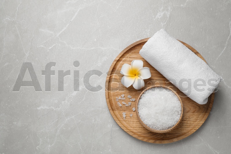 Sea salt, towel and flower on grey marble table, top view with space for text. Spa treatment