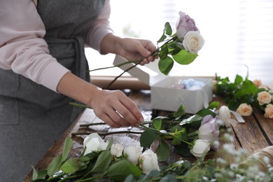 Florist making beautiful wedding bouquet at wooden table, closeup