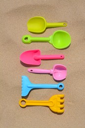 Set of colorful beach toys on sand, flat lay