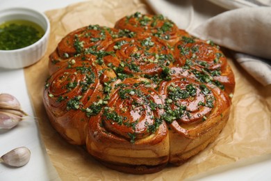 Traditional Ukrainian garlic bread with herbs (Pampushky) on white wooden table, closeup