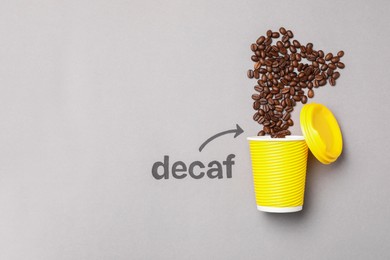 Photo of Word Decaf and arrow pointing at takeaway paper cup with coffee beans on light grey background, flat lay. Space for text