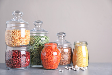 Jars with different cereals on grey table