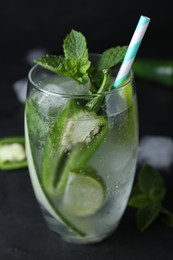 Photo of Spicy cocktail with jalapeno, cucumber, lime and mint on black table, closeup