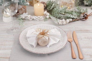Photo of Festive place setting with beautiful dishware, cutlery and decor for Christmas dinner on white wooden table