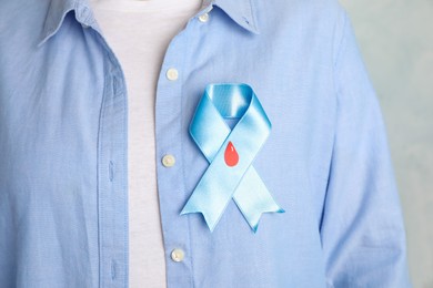 Photo of Woman with light blue ribbon and paper blood drop, closeup. World Diabetes Day