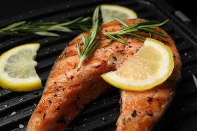 Photo of Cooking salmon. Grill with tasty fish steak, lemon and rosemary, closeup