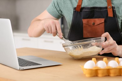 Photo of Man learning to cook with online video at wooden table indoors, closeup. Time for hobby