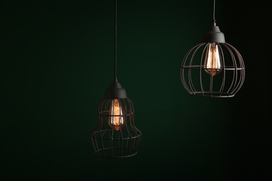 Photo of Hanging lamp bulbs in chandeliers against green background