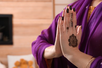 Woman with henna tattoos on hands indoors, closeup and space for text. Traditional mehndi ornament