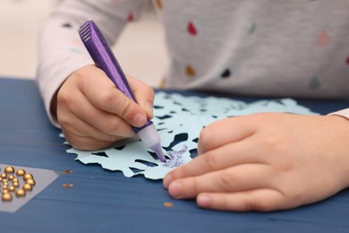 Little child making Christmas craft at blue wooden table, closeup