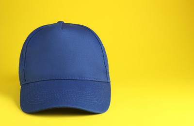 Stylish blue baseball cap on yellow background. Space for text