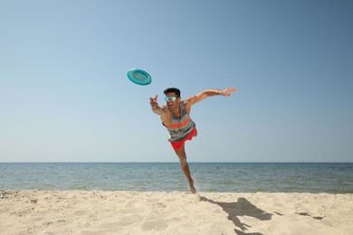 Sportive man jumping while trying to catch flying disk at beach