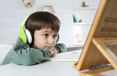 Photo of Cute little boy with modern tablet studying online at home. E-learning
